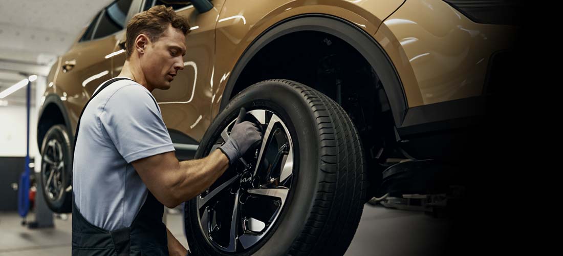 Mechanik serwisu Kia wymienia koło w samochodzie w autoryzowanym serwisie AS Motors